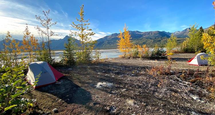 Campsite on a lakeside with colorful autumn trees and mountains.