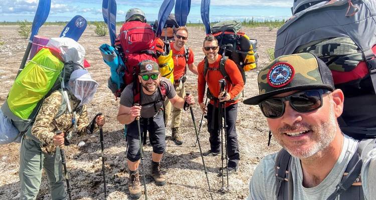 Group of hikers with backpacks posing in a wilderness setting.