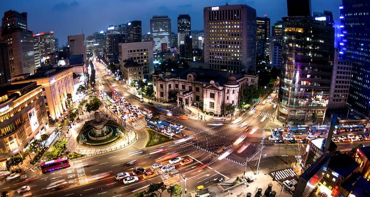 Paisaje urbano de Seúl por la noche con edificios iluminados y calles concurridas.