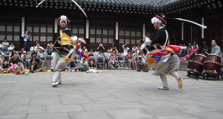 Actuación tradicional de danza coreana al aire libre con una audiencia observando.