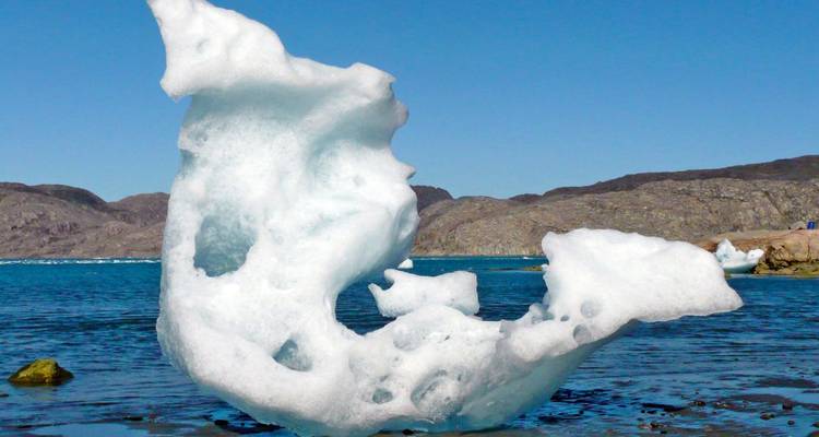 Iceberg floating in a calm blue sea.