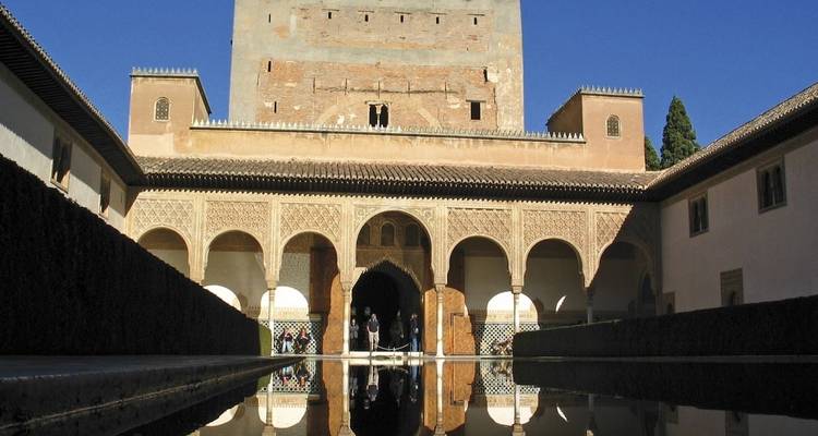 Vista interior del palacio de la Alhambra con reflejo en el agua.