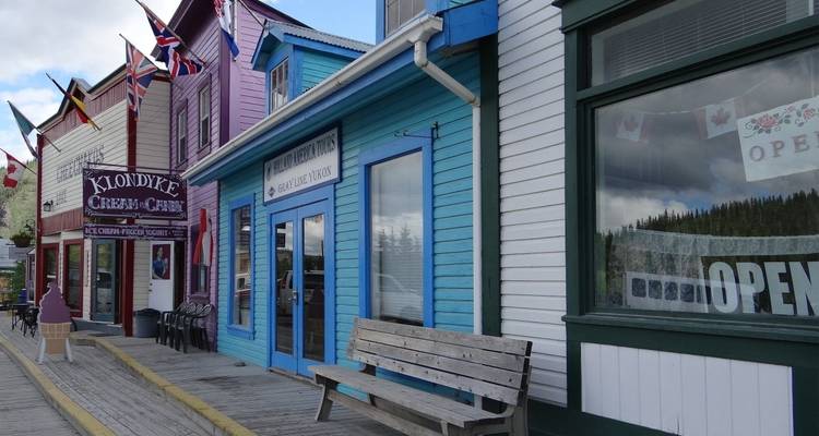 Colorful storefronts on a wooden boardwalk with flags.