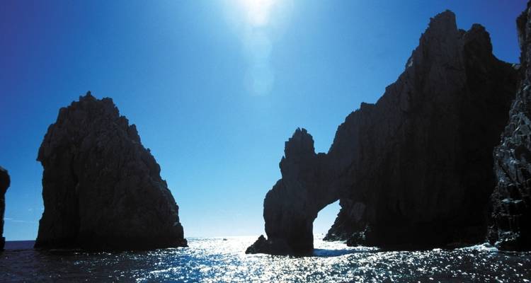 Arch-shaped rock formations silhouetted against the sea.