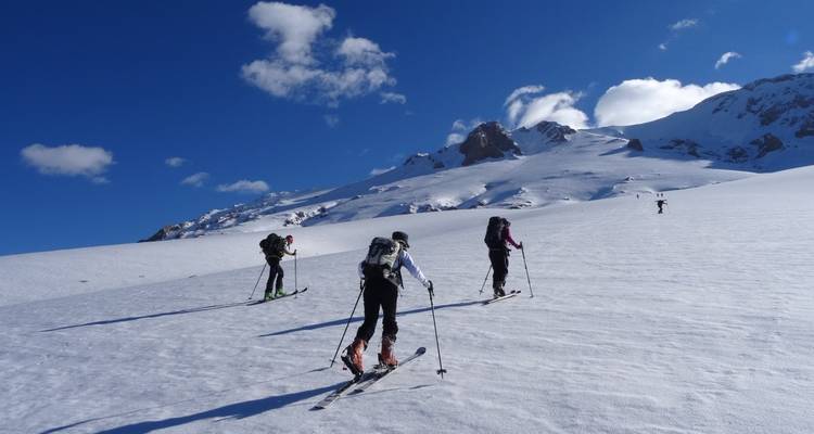 Personas esquiando cuesta arriba en un paisaje cubierto de nieve.