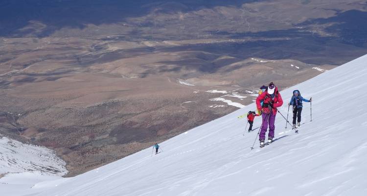 Grupo caminando por una colina empinada y nevada.