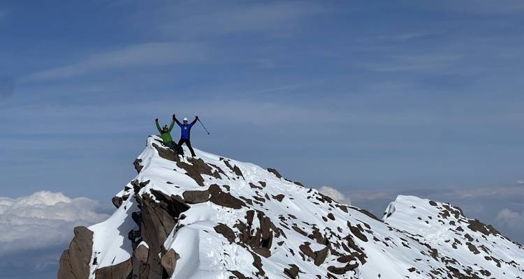 Two people celebrating on a snowy mountain peak.