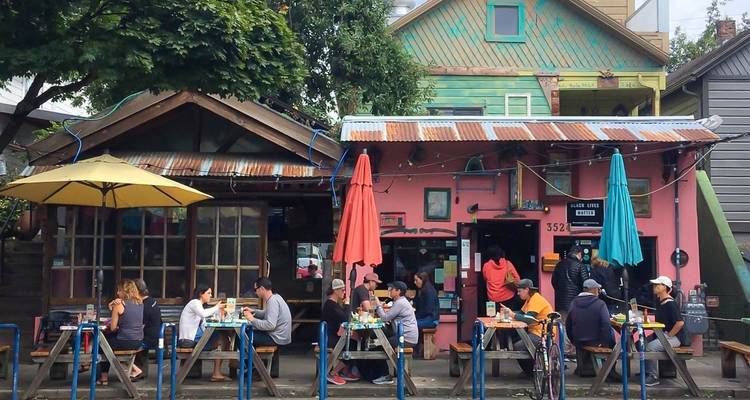 Menschen, die an Außentischen eines farbenfrohen Cafés speisen.