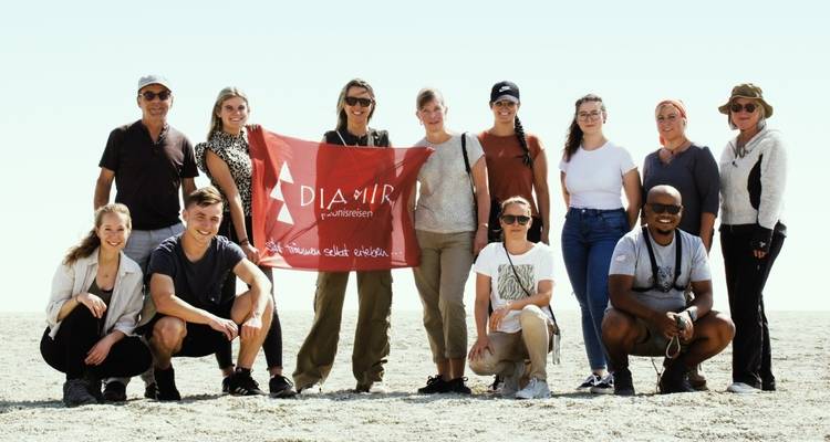 Photo de groupe de touristes tenant une bannière dans un désert.