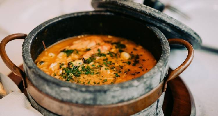 Ragoût de fruits de mer dans un pot en pierre servi sur une table.