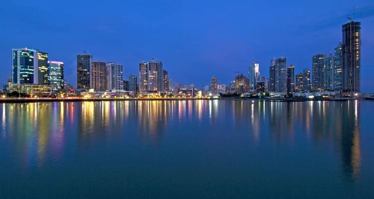 Panama City skyline at dusk with reflections in water.
