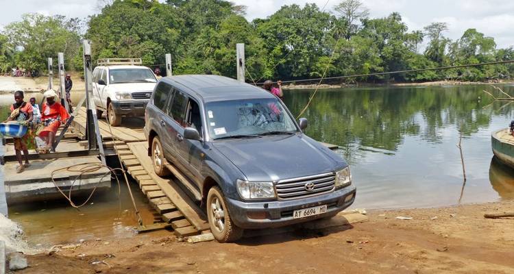 Autos überqueren einen Fluss auf einer provisorischen Brücke.