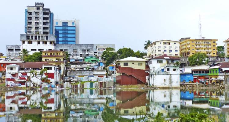 Bunte Gebäude, die sich in einem Gewässer spiegeln.