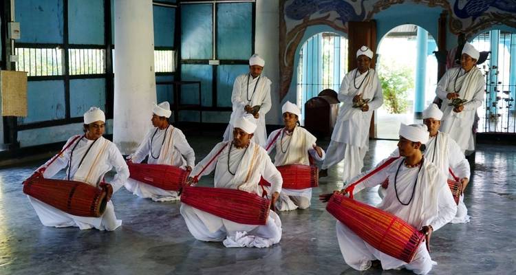 Eine Gruppe von Männern in traditioneller Kleidung, die drinnen mit Trommeln auftritt.