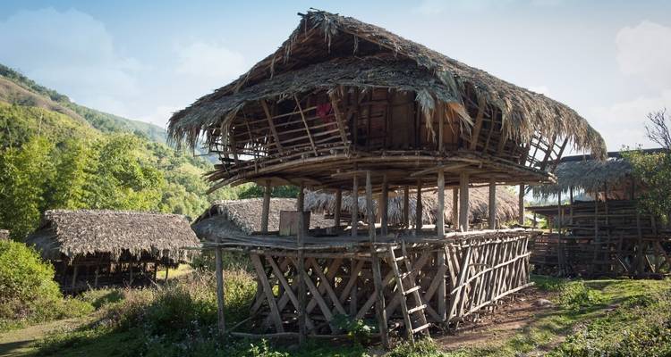 Traditionelle Pfahlbauten mit Strohdächern in ländlicher Umgebung.