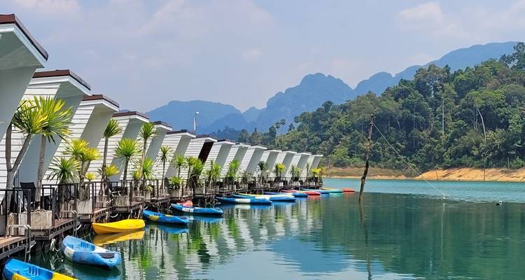 Bungalows flottants sur un lac calme avec des kayaks.
