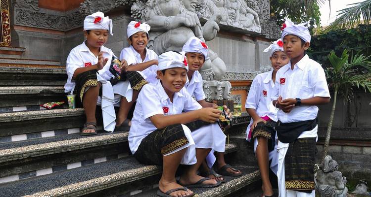Niños jóvenes con vestimenta tradicional sentados en escalones en Indonesia.