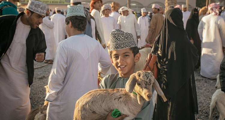 A lively market scene with people and livestock, possibly in Oman.
