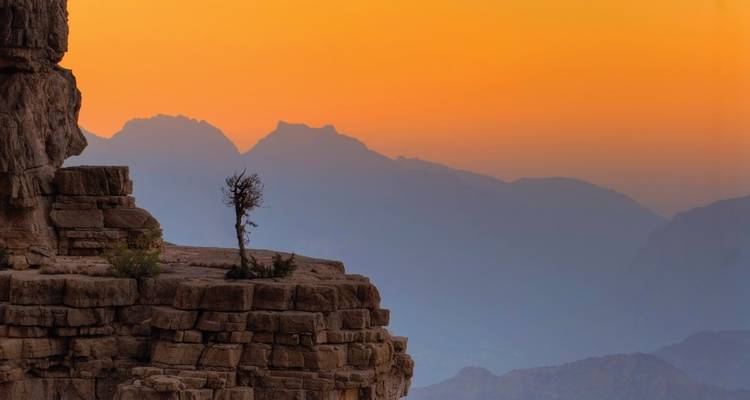A scenic view of mountains during sunset with an orange sky.