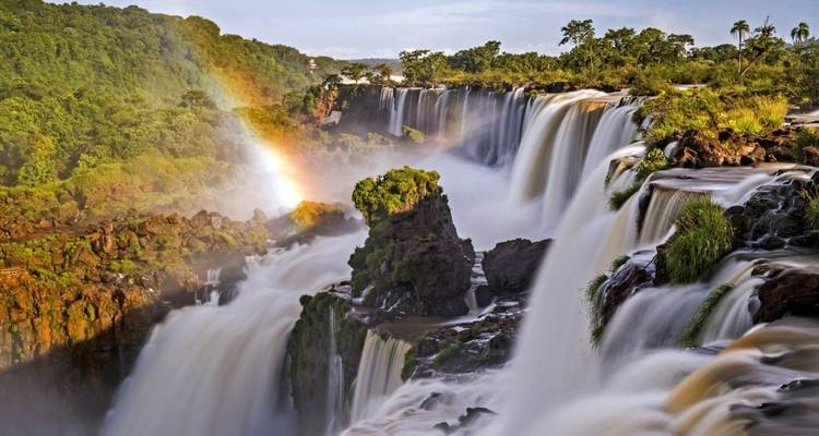 Majestätischer Wasserfall mit Regenbogen in üppiger Umgebung.