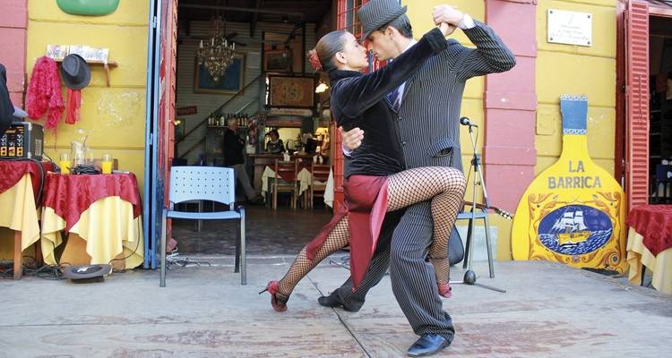 Paar tanzt Tango vor einem bunten Café.