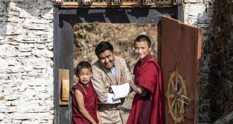 Two monks and a man posing at a temple entrance.