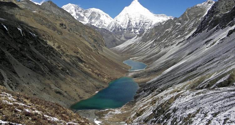 A valley with a river winding between snowy mountains.