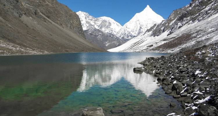 A serene lake with mountain reflections and snow-covered peaks.