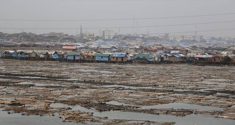 Waterfront view of a floating village with logs on the water.
