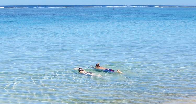 Two people snorkeling in clear blue water.