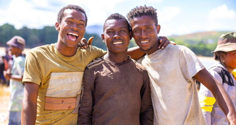 Drie glimlachende mannen die buiten poseren.