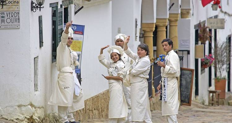 Gruppe von Köchen in weißen Uniformen, die auf einer Kopfsteinpflasterstraße posieren.