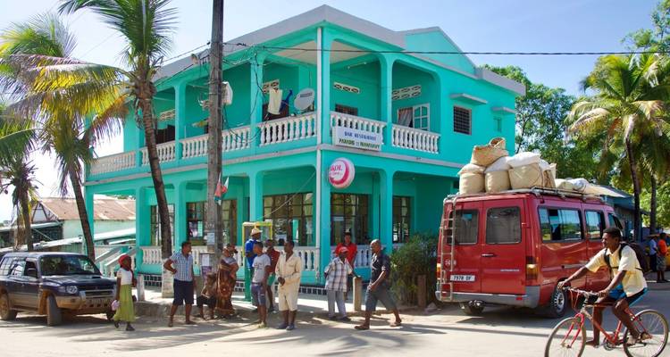 A bright blue building with a red bus and people gathered outside.