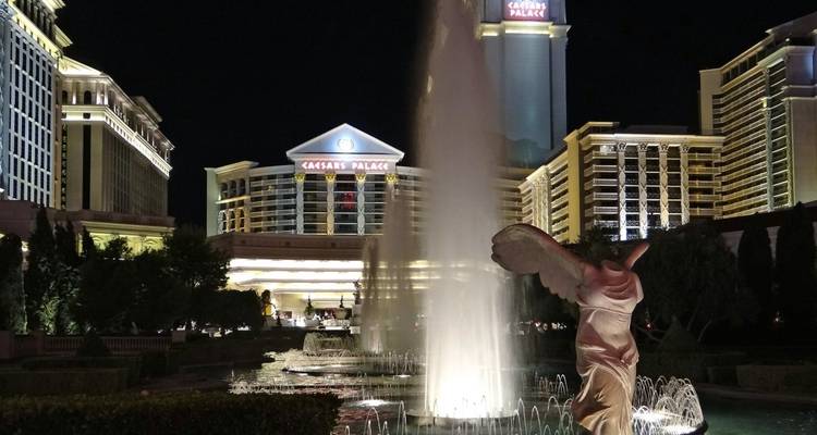 Fountain and statues lit up at night in front of Caesars Palace, Las Vegas.