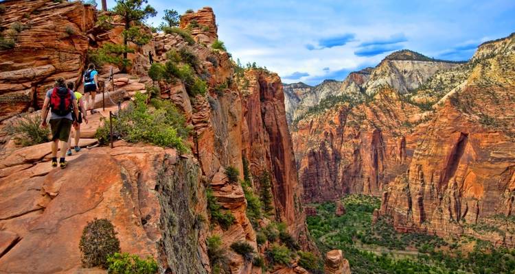 Hikers walking on a cliffside trail in a national park.