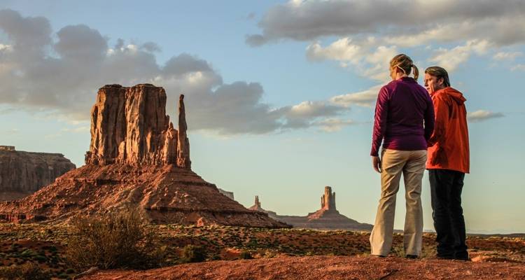 Two people observing rock formations in Monument Valley.