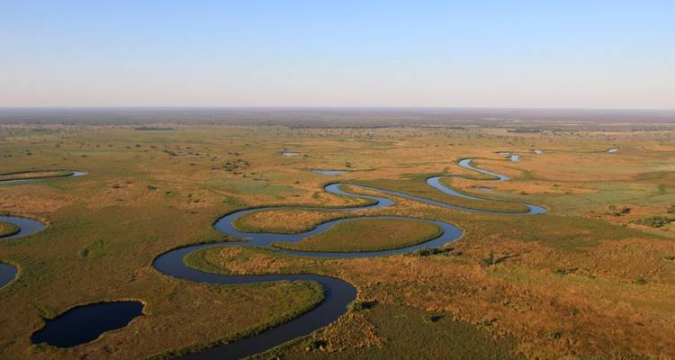 Aerial view of a winding river through a vast flat landscape.
