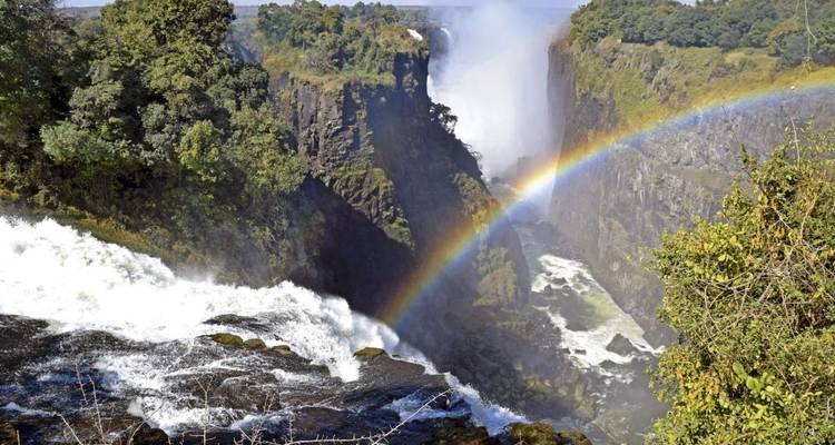 Victoria Falls with a rainbow forming in the mist.
