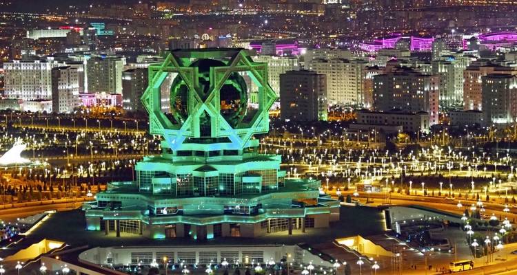 Paysage urbain illuminé la nuit avec un bâtiment à l'architecture unique.