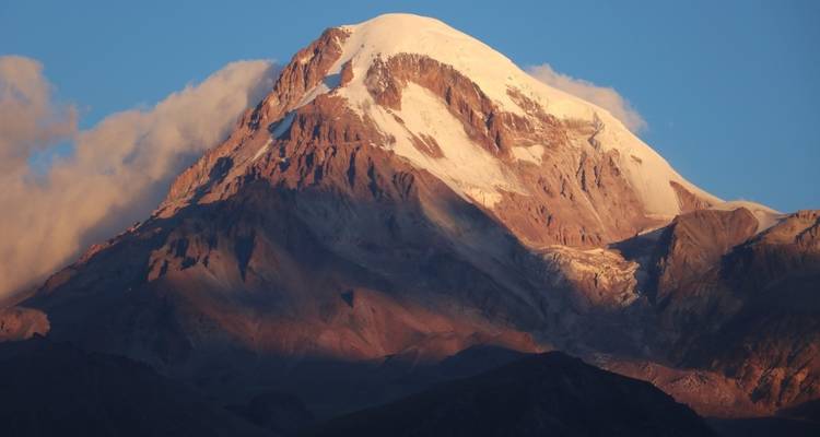 Sommet de montagne enneigé illuminé par la lumière du soleil couchant.