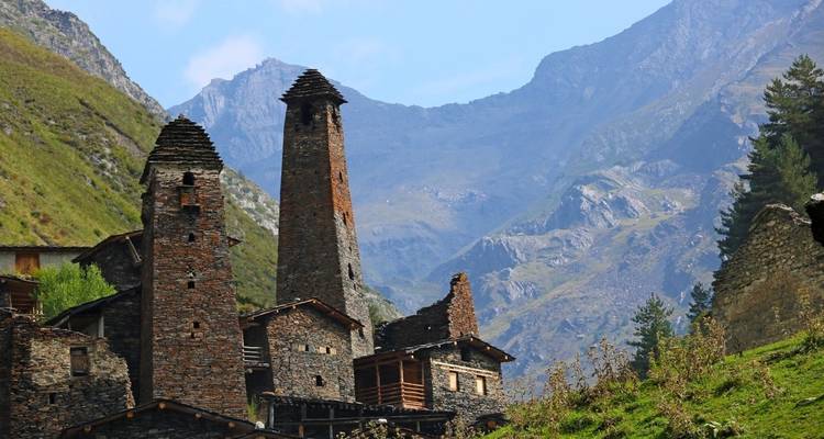 Anciennes tours de pierre dans un cadre montagneux sous un ciel dégagé.