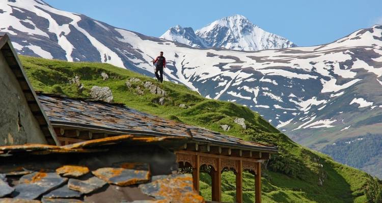 Personne faisant de la randonnée dans un paysage montagneux pittoresque avec des sommets enneigés.
