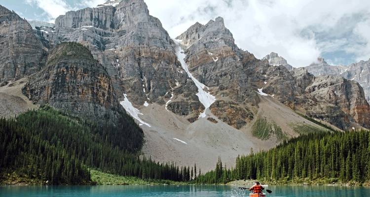 Personne faisant du kayak dans un lac entouré de montagnes.