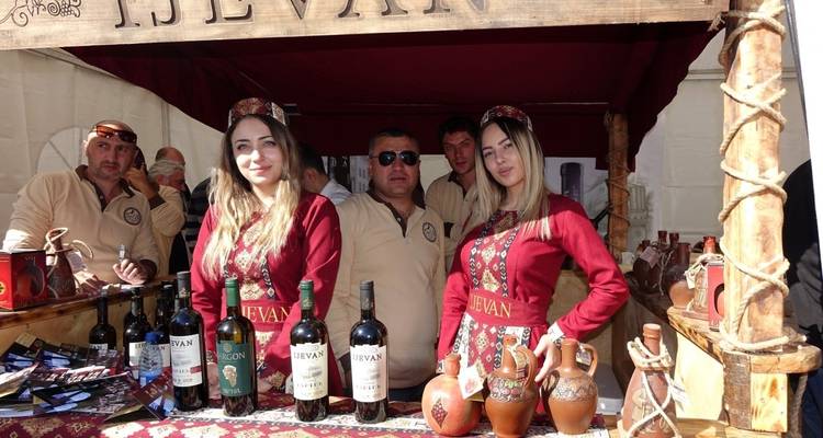 A group of people in traditional attire at a wine festival stand.