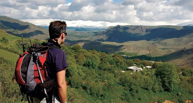 A person with a backpack enjoying a panoramic mountain view.