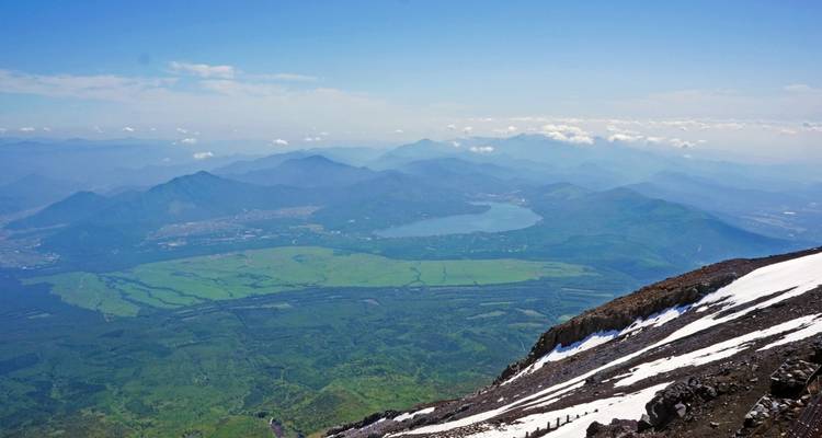 Vue expansive d'une vallée avec des montagnes et un lac.