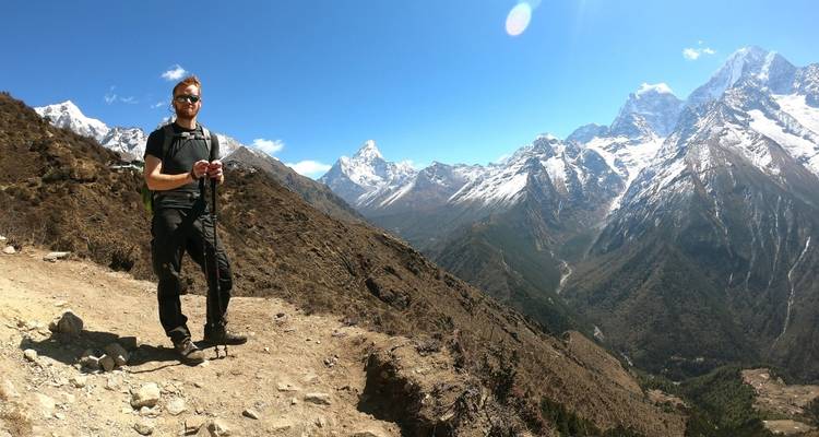 Person hiking on a trail with snow-capped mountains in the background.