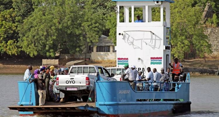 Personas y vehículos en un ferry cruzando una masa de agua.