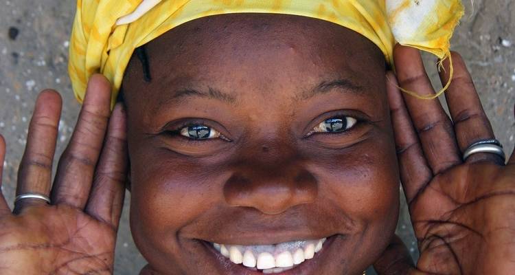 Primer plano de una persona sonriente que lleva un pañuelo colorido en la cabeza.