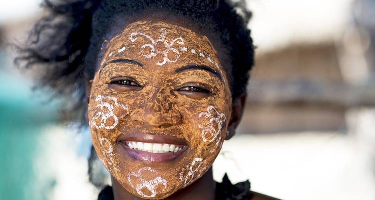 Personne avec peinture faciale traditionnelle souriant chaleureusement.